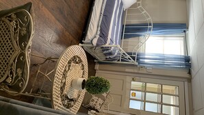 A room with a bed, a chair, a small table with a plant, and a window with curtains. - 1 bedroom apt.Minutes to Encore Casino and Boston. (Revere)
