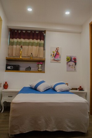 Un dormitorio con una cama, una estantería decorada y una obra de arte en la pared.
