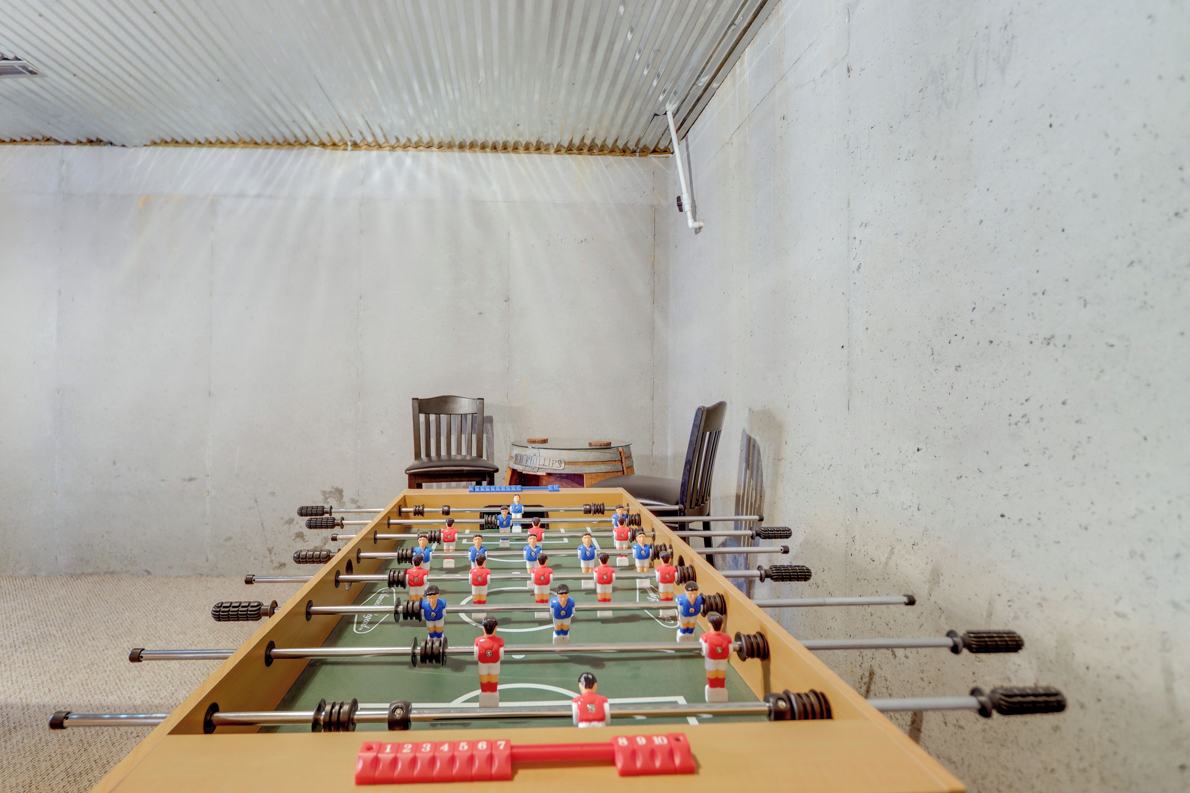 A foosball table in a room with a white wall and a ceiling with a corrugated design.