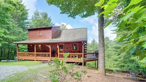 A log cabin with a porch, surrounded by trees and a gravel driveway. - Hot Tub & Game Room: Charming Morganton Cabin! (Morganton)