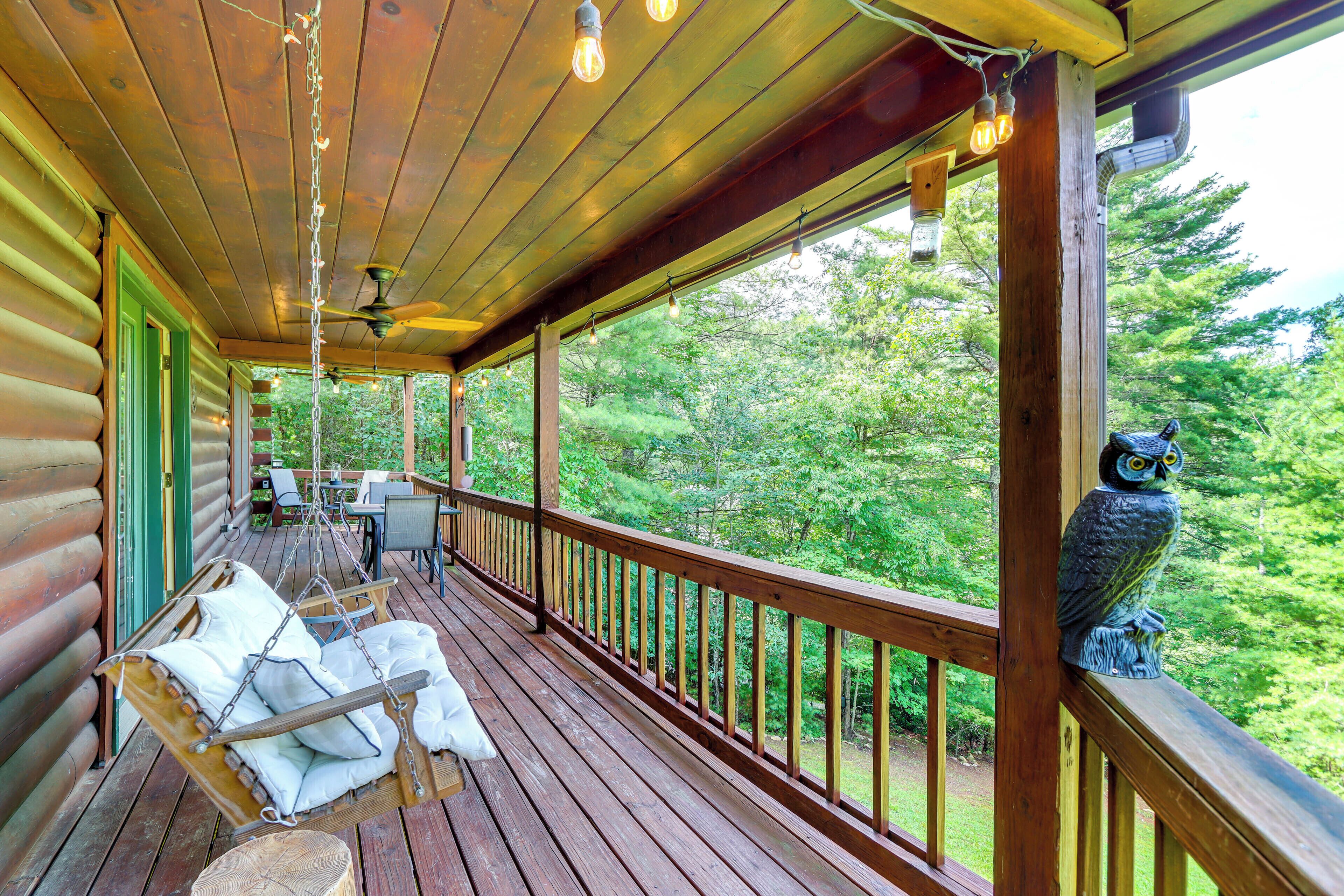 A wooden deck with a hanging chair and a statue of an owl.