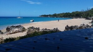 Ein Strand mit klarem blauen Wasser, einem Sandufer und Felsenformationen.