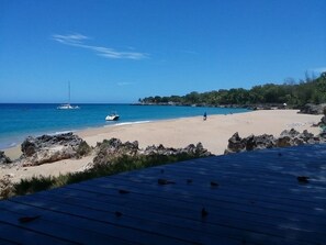 Ein Strand mit klarem blauen Wasser, einem Sandufer und Felsenformationen.
