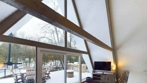 Ein Zimmer mit hohen Decken und einem großen Fenster mit Blick auf eine verschneite Landschaft.