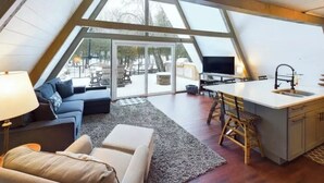 Ein gemütliches, modernes Lofts Schlafzimmer mit großem Dachfenster, einer bequemen Couch, einer Leseecke und einer Küchenzeile.