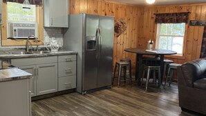 A compact kitchen with a refrigerator, sink, and wooden flooring. - Adirondack Escape on the Great Sacandaga Lake (Hadley)