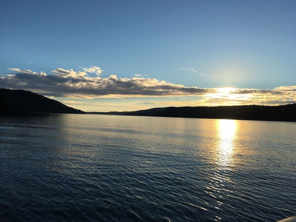 A calm lake at sunset with a clear sky and distant hills. - Adirondack Escape on the Great Sacandaga Lake (Hadley)