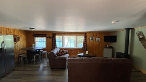 A cozy cabin interior with a wooden interior, a dining area, a sofa, and a television. - Adirondack Escape on the Great Sacandaga Lake (Hadley)