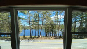 A view through a window of a road with a lake and trees in the background. - Adirondack Escape on the Great Sacandaga Lake (Hadley)