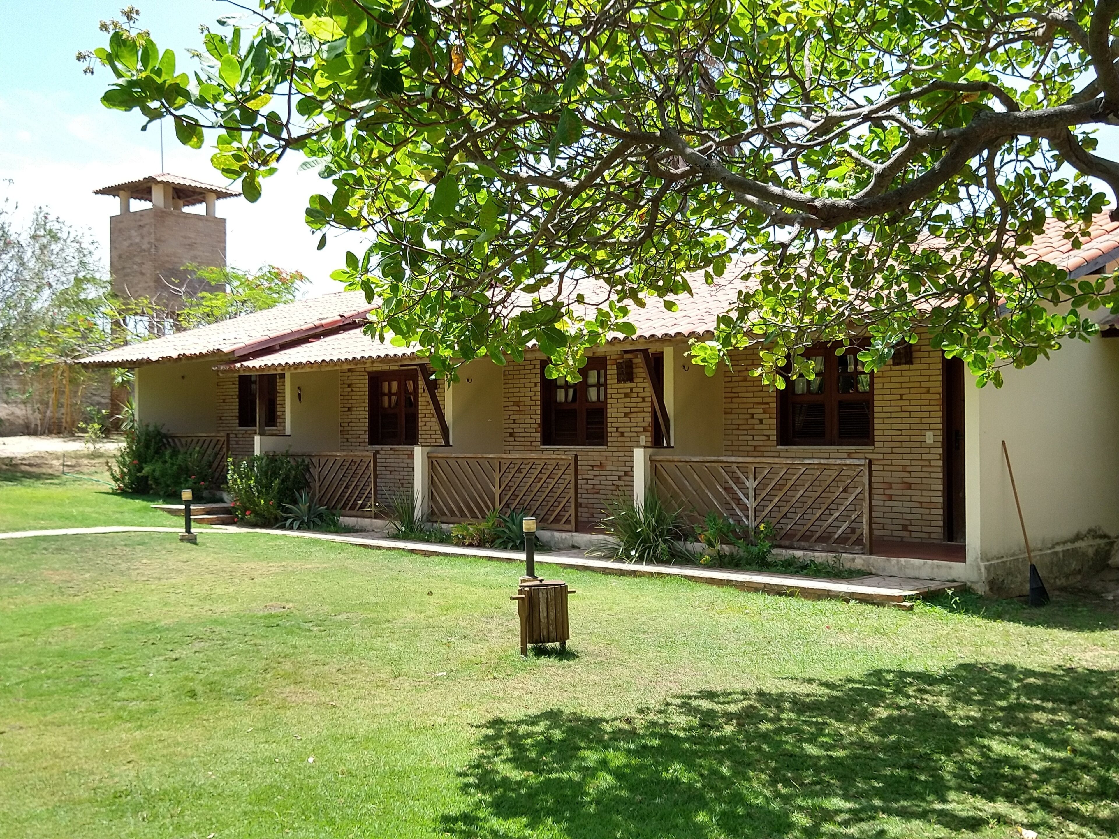 A two-story house with a brick facade, a tiled roof, and a small tower-like structure on the roof.