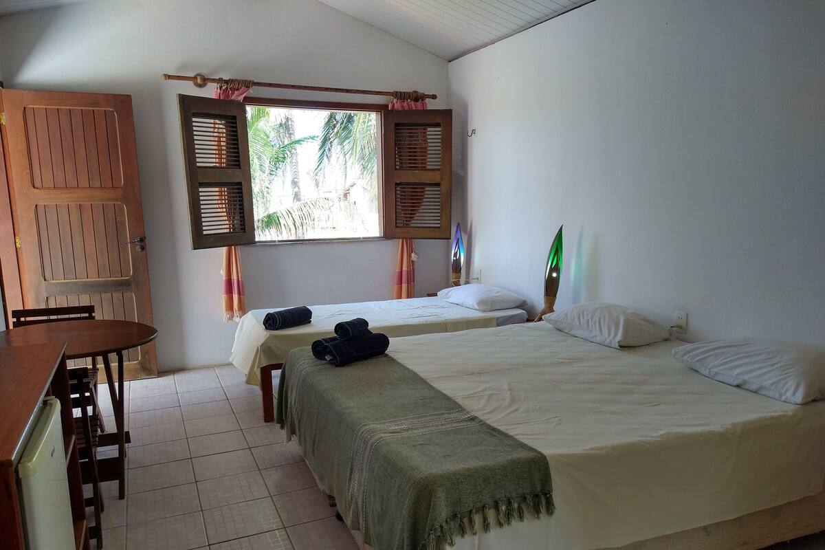 A room with two beds, a desk, and a window with shutters.