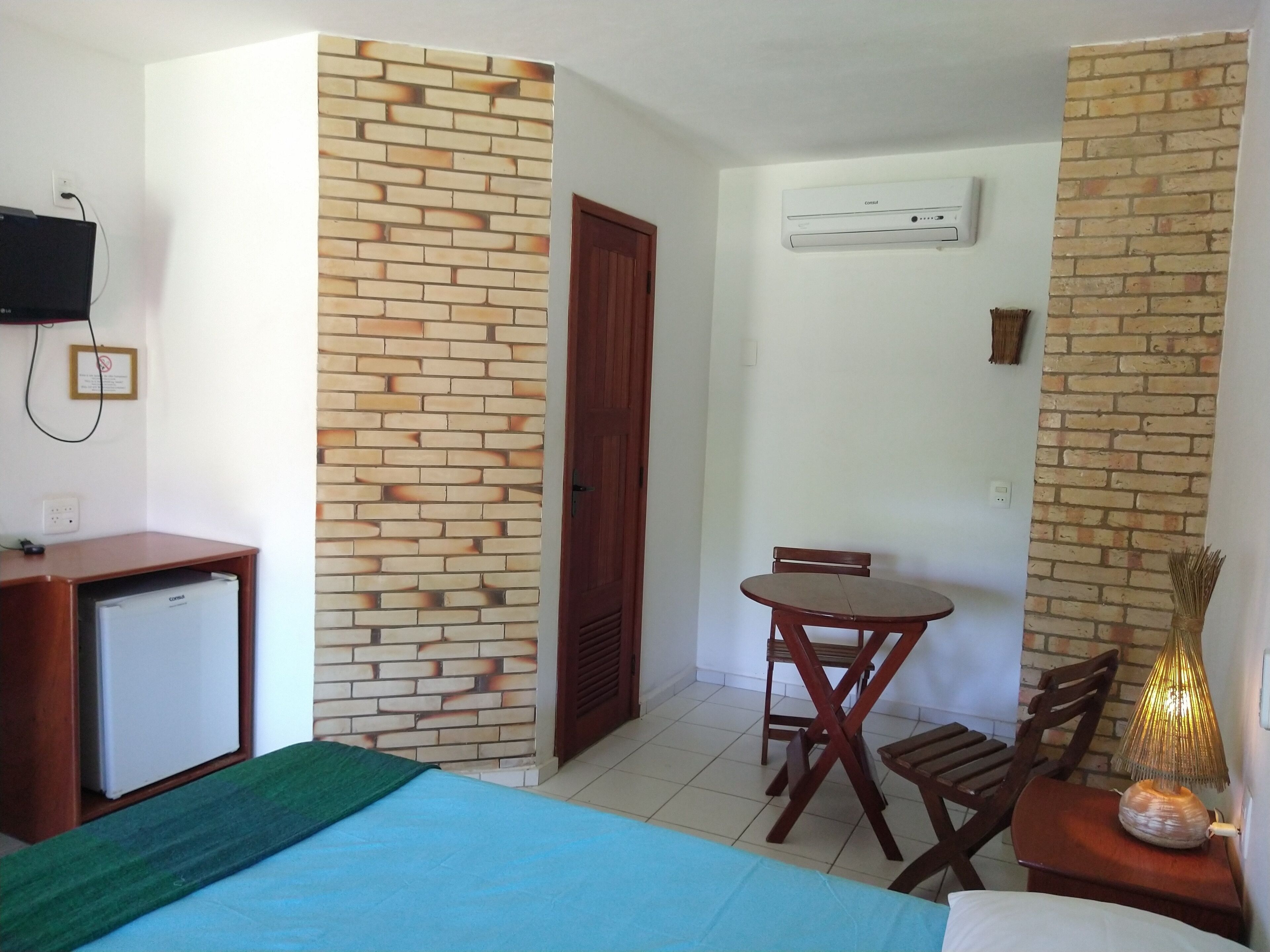 Una habitación con cama, escritorio, silla, mesa y lámpara.