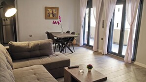 Una sala de estar moderna con un sofá, una mesa de centro, una mesa de comedor con sillas y un cuadro en la pared.
