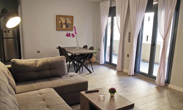 A modern living room with a sofa, a coffee table, a dining table with chairs, and a painting on the wall. - Athens Heart Renovated Apartment (Athina)