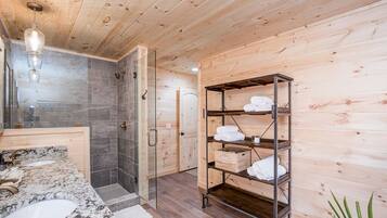 A bathroom with a wooden interior, a glass shower enclosure, a marble sink, and a towel rack.