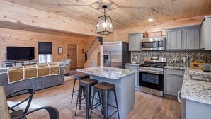 Una cocina moderna con encimeras de granito, electrodomésticos de acero inoxidable y techo de madera.