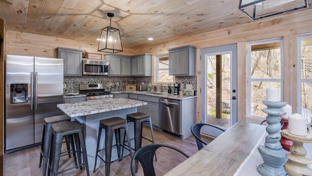 Una cocina moderna con techo de madera, electrodomésticos de acero inoxidable y una isla grande con taburetes de bar.