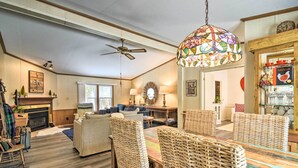 A cozy living room with a fireplace, wicker furniture, and a stained glass ceiling light. - Woodland Retreat: Near Trails, Golf & Wineries! (Harbor Springs)