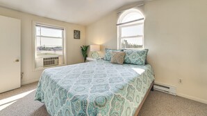 Ein Schlafzimmer mit einem großen Bett, zwei Fenstern, einem Heizkörper und einer Tür.