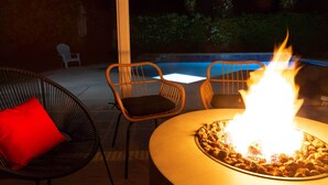 An outdoor seating area with wicker chairs and a table with a fire feature.