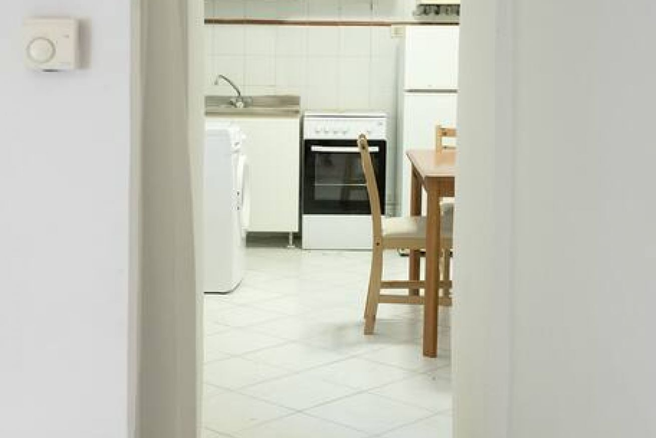 Una cocina con armarios blancos, una estufa y una silla.