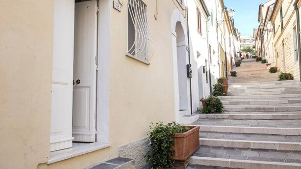 Un vicolo stretto con edifici su entrambi i lati, una porta bianca e una finestra con sbarre metalliche.
