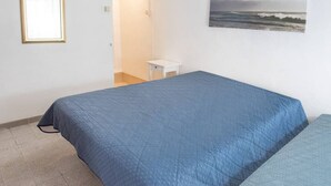 Una camera da letto con un letto, un comodino, un quadro appeso al muro e una porta che dà su un'altra stanza.