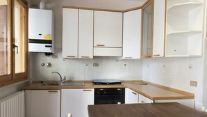 A kitchen with white cabinets, a stove, a sink, and a wooden table. - M255 - Marcelli, three-room apartment with porch 250m from the sea (Marcelli)