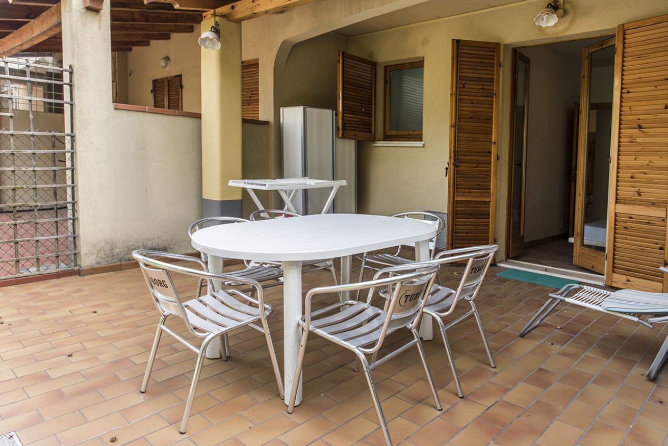 A round table with six chairs, a refrigerator, and wooden shutters on the walls.