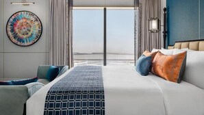 A modern hotel room with a large bed, a view of the sea, and a colorful abstract painting on the wall. - Grand Lisboa Palace Macau (Cotai)