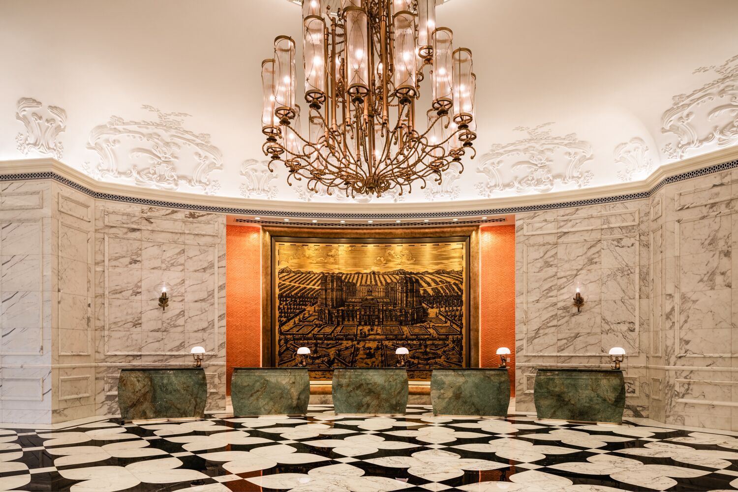 Um hall de entrada luxuoso com paredes de mármore, piso estampado e um imponente candelabro.