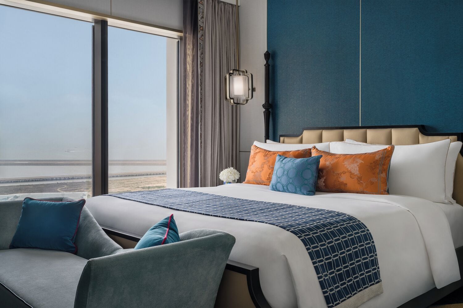 Ein Hotelzimmer mit einem großen Bett, Blick auf den Strand und einem Vorhangfenster.