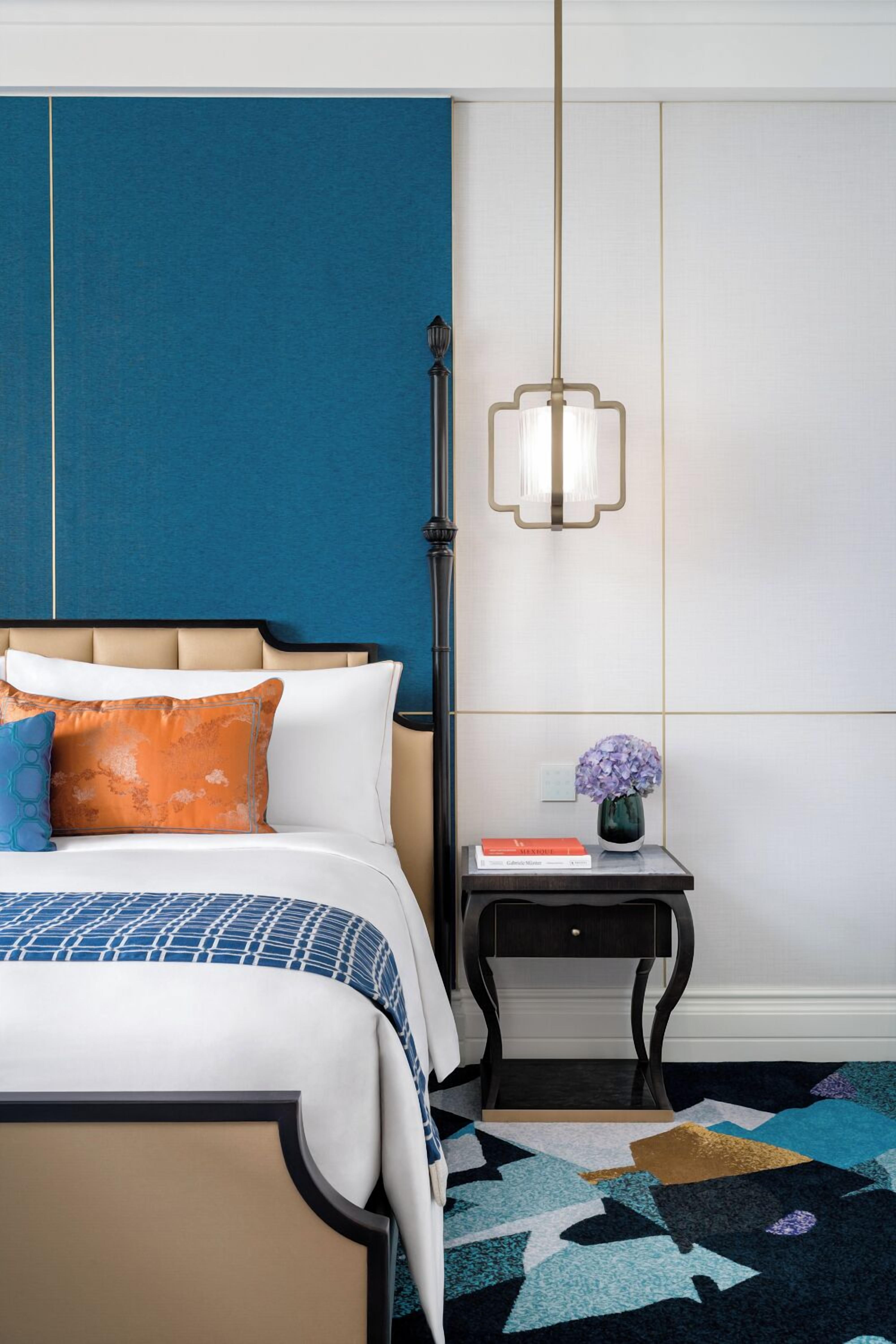 A neatly arranged bedroom with a bed, bedside table, and a hanging light fixture.