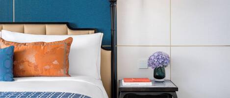 A neatly arranged bedroom with a bed, bedside table, and a hanging light fixture.