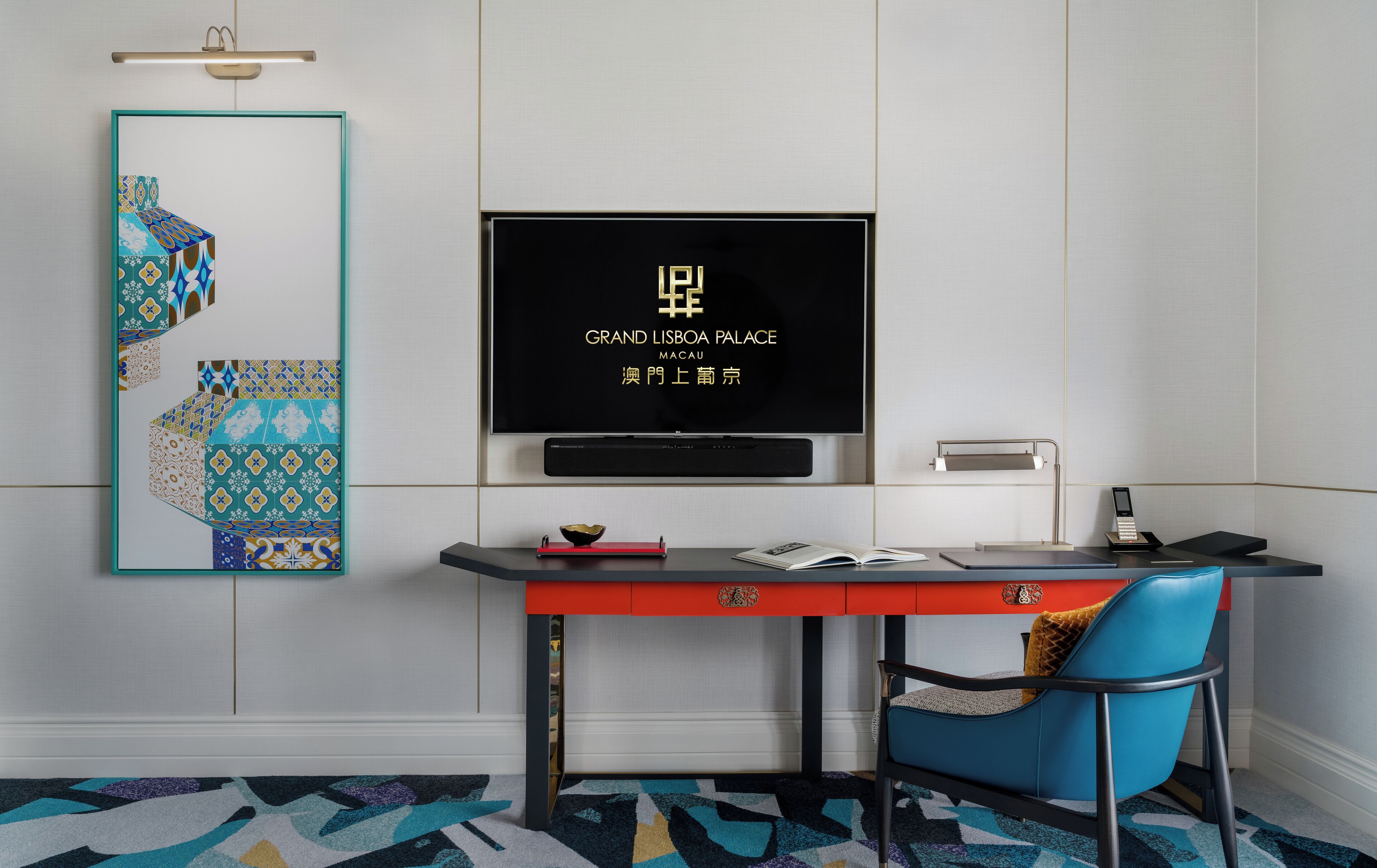 A modern room with a desk, chair, television, and decorative wall piece.