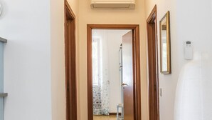 Un corridoio con una porta in legno, uno specchio e un termostato sulla parete.