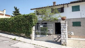 Edificio residenziale con ingresso carrabile, porte numerate e un muro in mattoni.