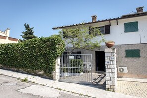 A residential building with a gated entrance, numbered doors, and a brick wall.