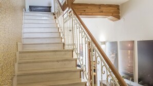 Un escalier avec une rampe en bois et des balustrades blanches, menant à une pièce dotée d’une grande fenêtre et d’un téléviseur à écran plat.