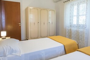 Une chambre d’hôtel avec un lit, une armoire et une fenêtre avec des rideaux.