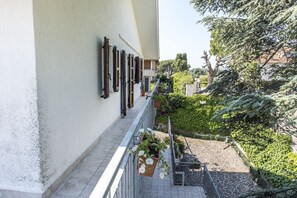 Un balcon orné de plantes en pot et doté d’une rambarde en métal.