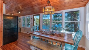 Uma sala de jantar de madeira com uma mesa, cadeiras e um lustre.