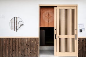 A traditional Japanese entrance with a sliding door, a circular wall decoration, and a wooden panel design.