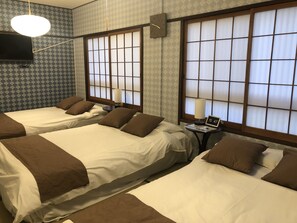 A hotel room with two beds, a clock, and a table with a lamp.