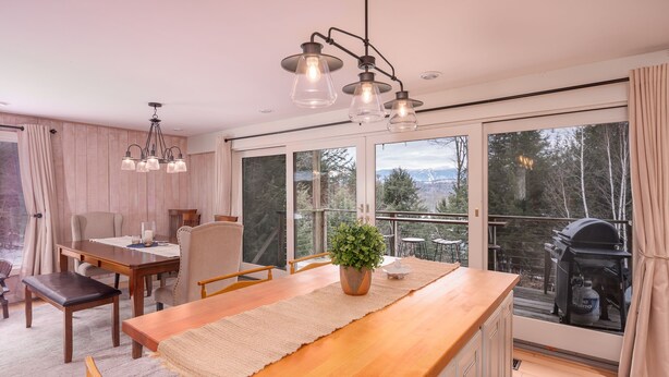 A modern kitchen with a wooden island, large windows, and a view of the outdoors. - Classic Stowe Ski 3 Bedroom Chalet by RedAwning (Stowe)