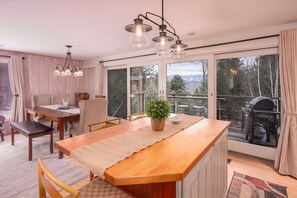 A modern kitchen with a wooden island, large windows, and a view of the outdoors. - Classic Stowe Ski 3 Bedroom Chalet by RedAwning (Stowe)