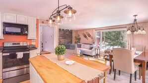 A modern kitchen with a central island, built-in appliances, and a dining area with a view. - Classic Stowe Ski 3 Bedroom Chalet by RedAwning (Stowe)