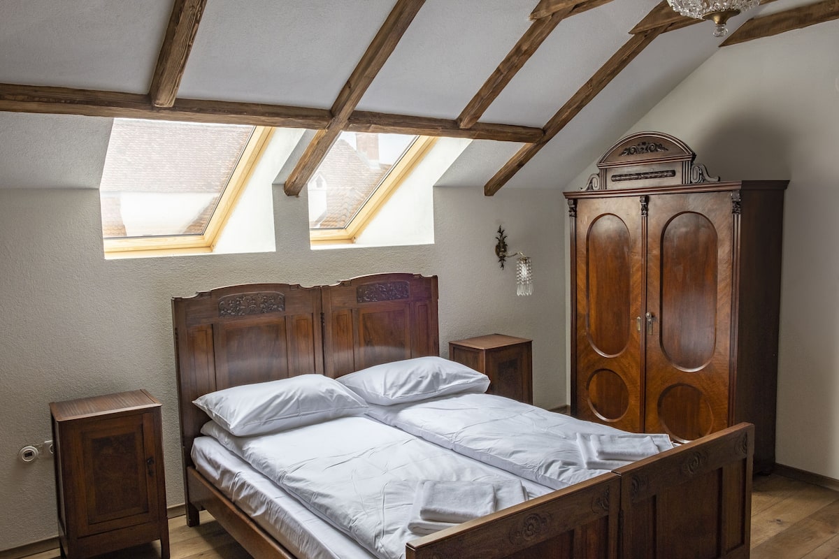 A bedroom with a wooden bed, a wardrobe, and a skylight.