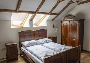 Une chambre à coucher avec un lit en bois, une armoire et une lucarne.