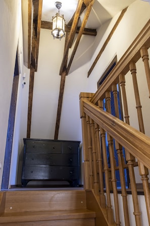 Un escalier en bois avec une commode sombre au bas.